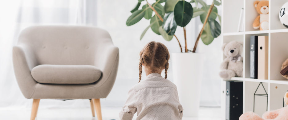 Child Sitting On Floor With Back facing To Camera