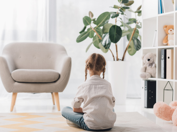 Child Sitting On Floor With Back facing To Camera
