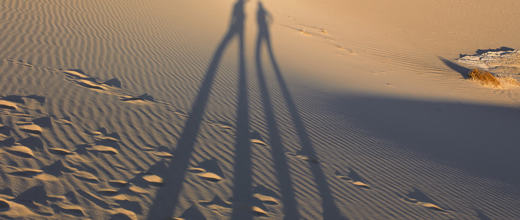 shadow of two standing people in the sand