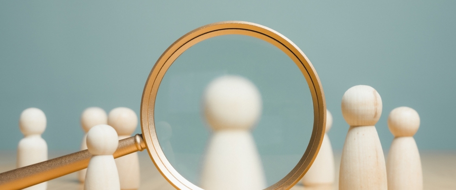 Wooden figure under magnifying glass