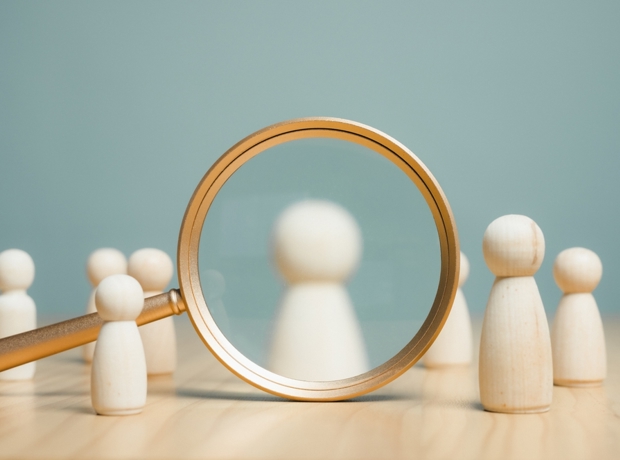 Wooden figure under magnifying glass