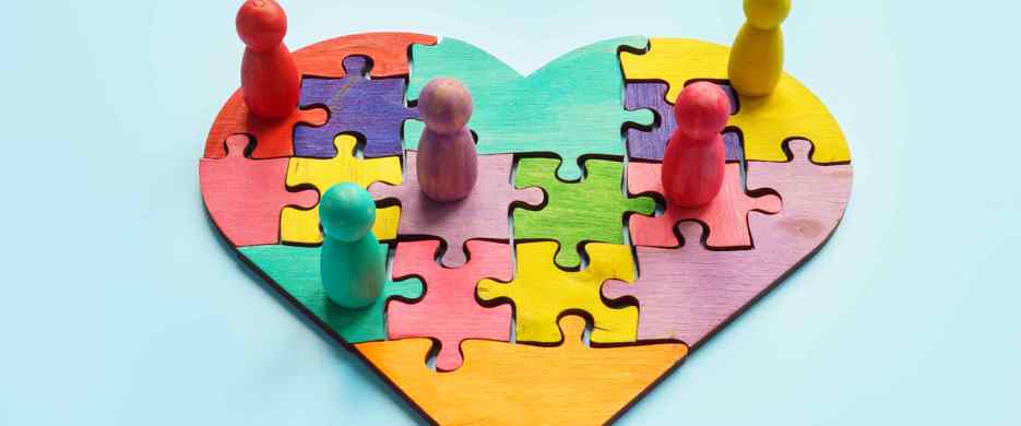 different coloured pieces jigsaw heart with figures sitting on top