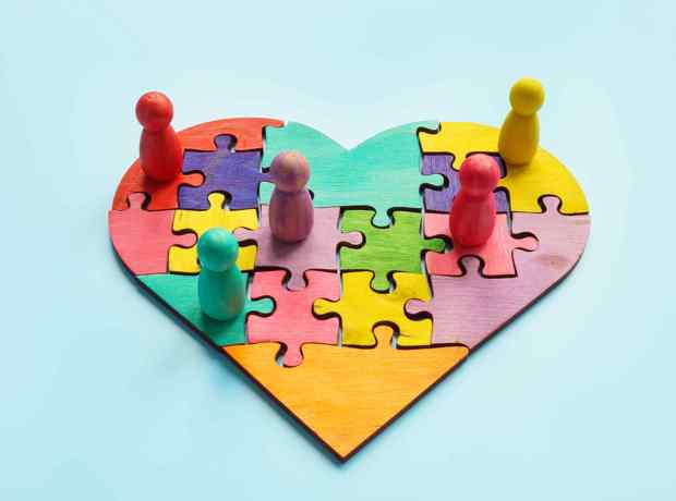 different coloured pieces jigsaw heart with figures sitting on top
