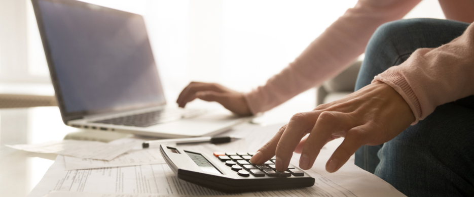 person using calculator and computer