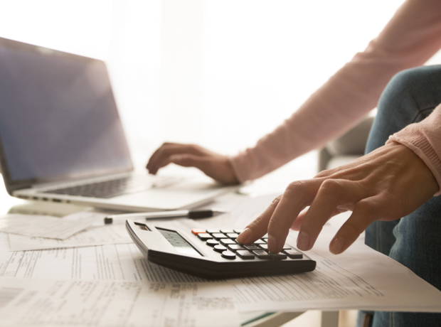 person using calculator and computer