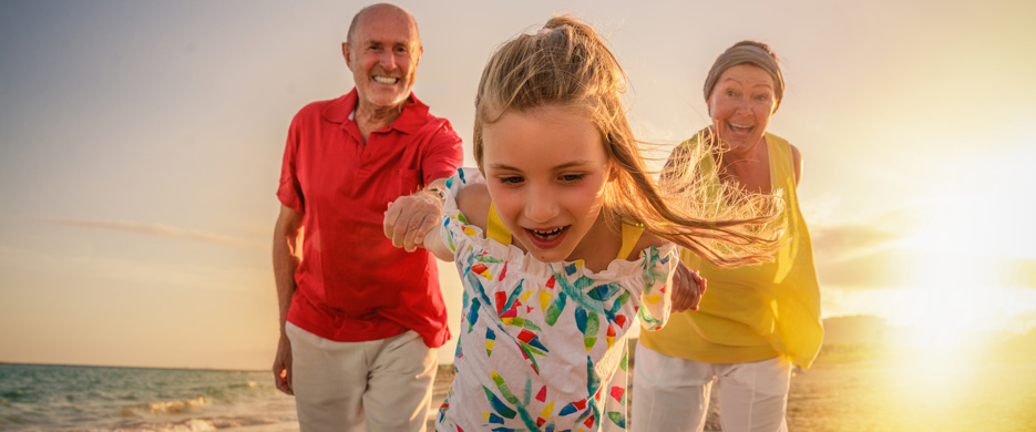 grandparents with grandchild on beach