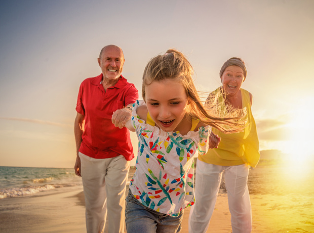 grandparents with grandchild on beach
