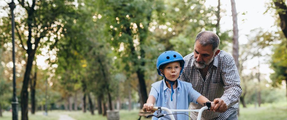 Grandfather helping grandchild to ride cycle