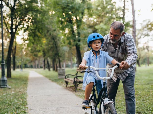 Grandfather helping grandchild to ride cycle